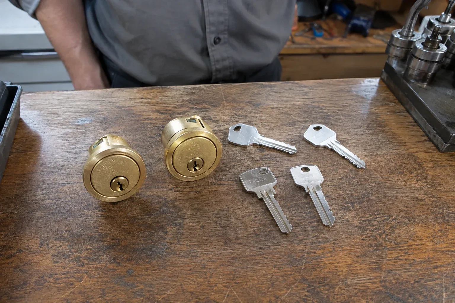 Two detached brass lock cylinders and four house keys on a wooden counter. — Lock Rekeying, Niagara Falls