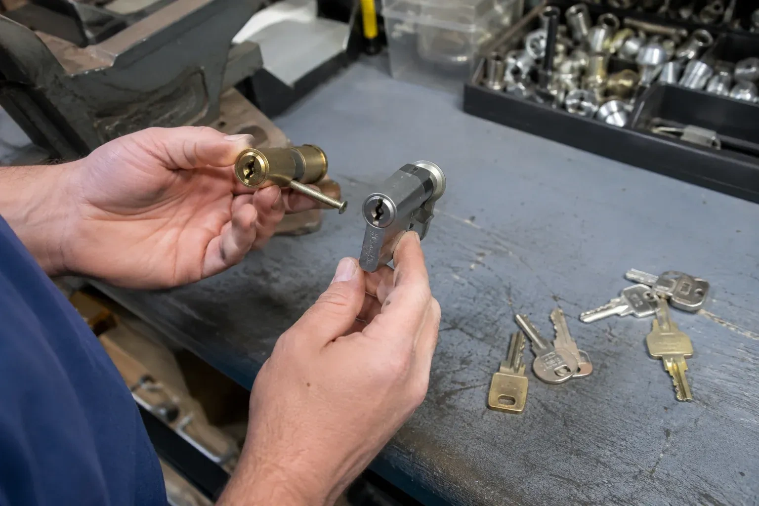 Hands comparing detached lock cylinders beside loose keys on a workbench. — Broken Key Extraction, Queensway Gardens